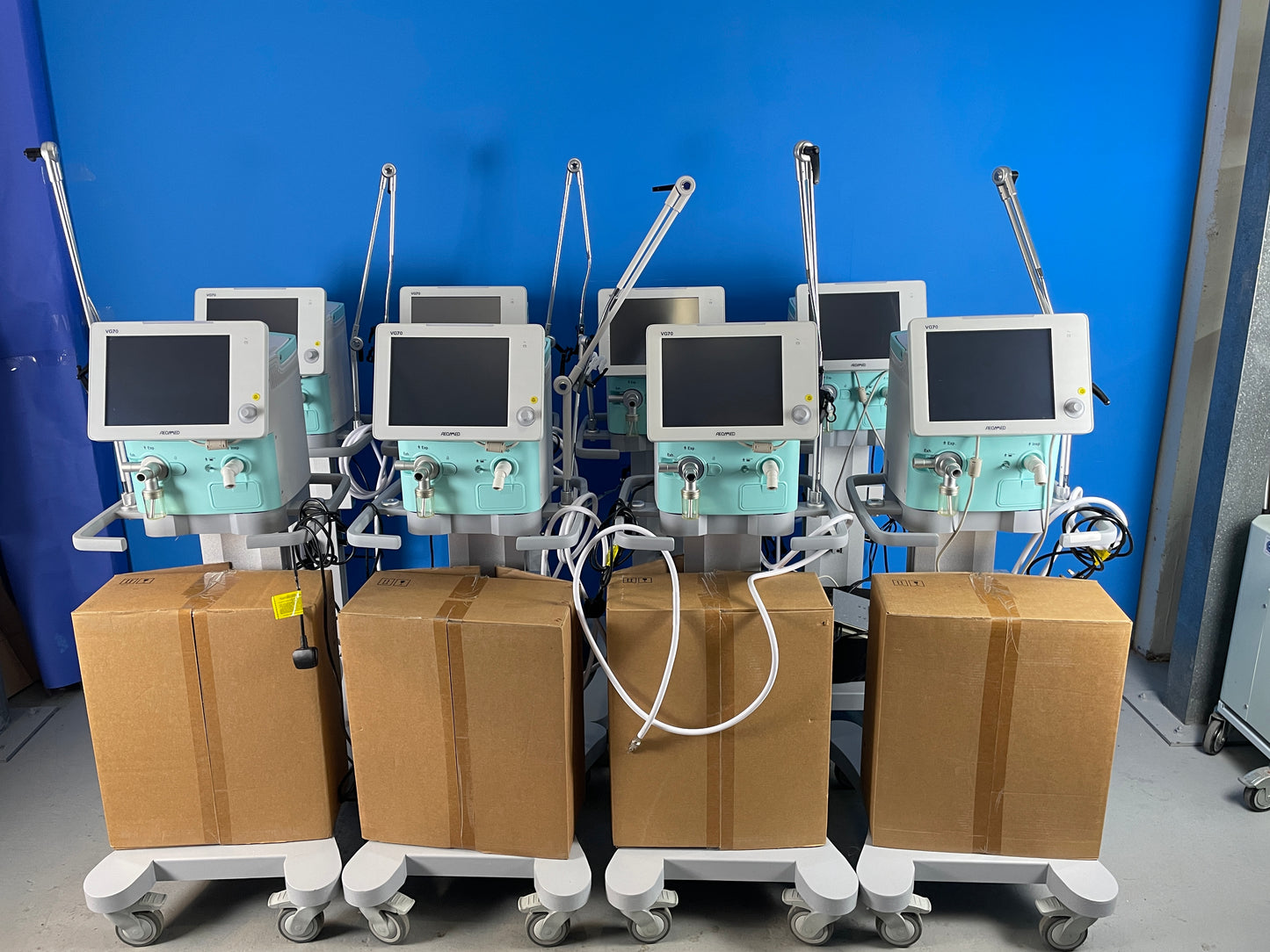 A large number of Quantity of Aenomed VG70 Ventilators with accessories available ,Display with blue studio background